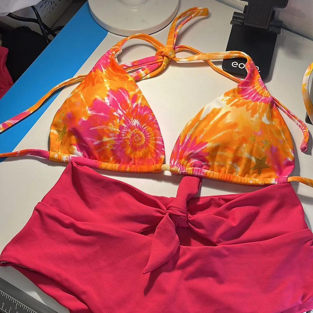 A bikini with an orange tie dye top and red high waisted bottoms