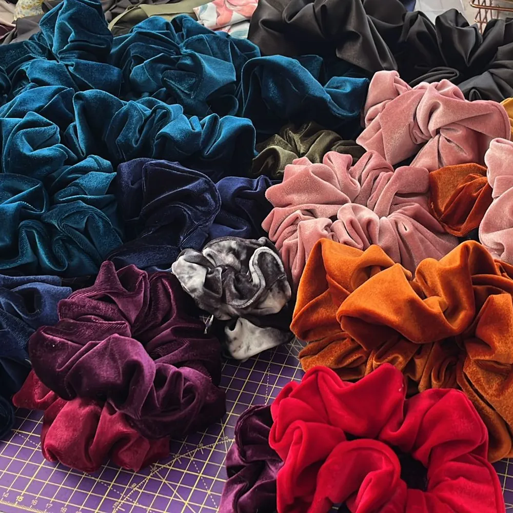 A pile of velvet scrunchies in teal, navy, plum, orange, pink and red